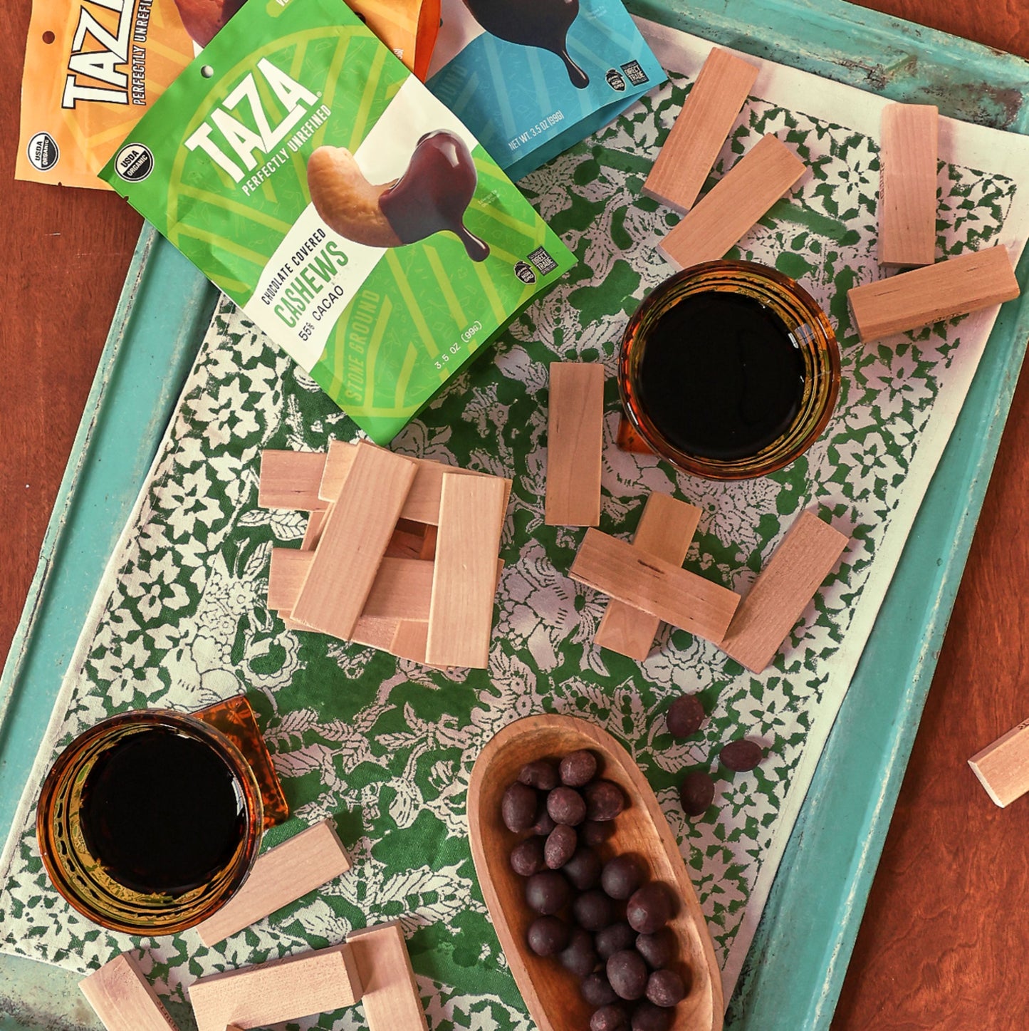 Bag of Chocolate Covered Cashews in a family game night setting with an open bowl of chocolate covered cashews.