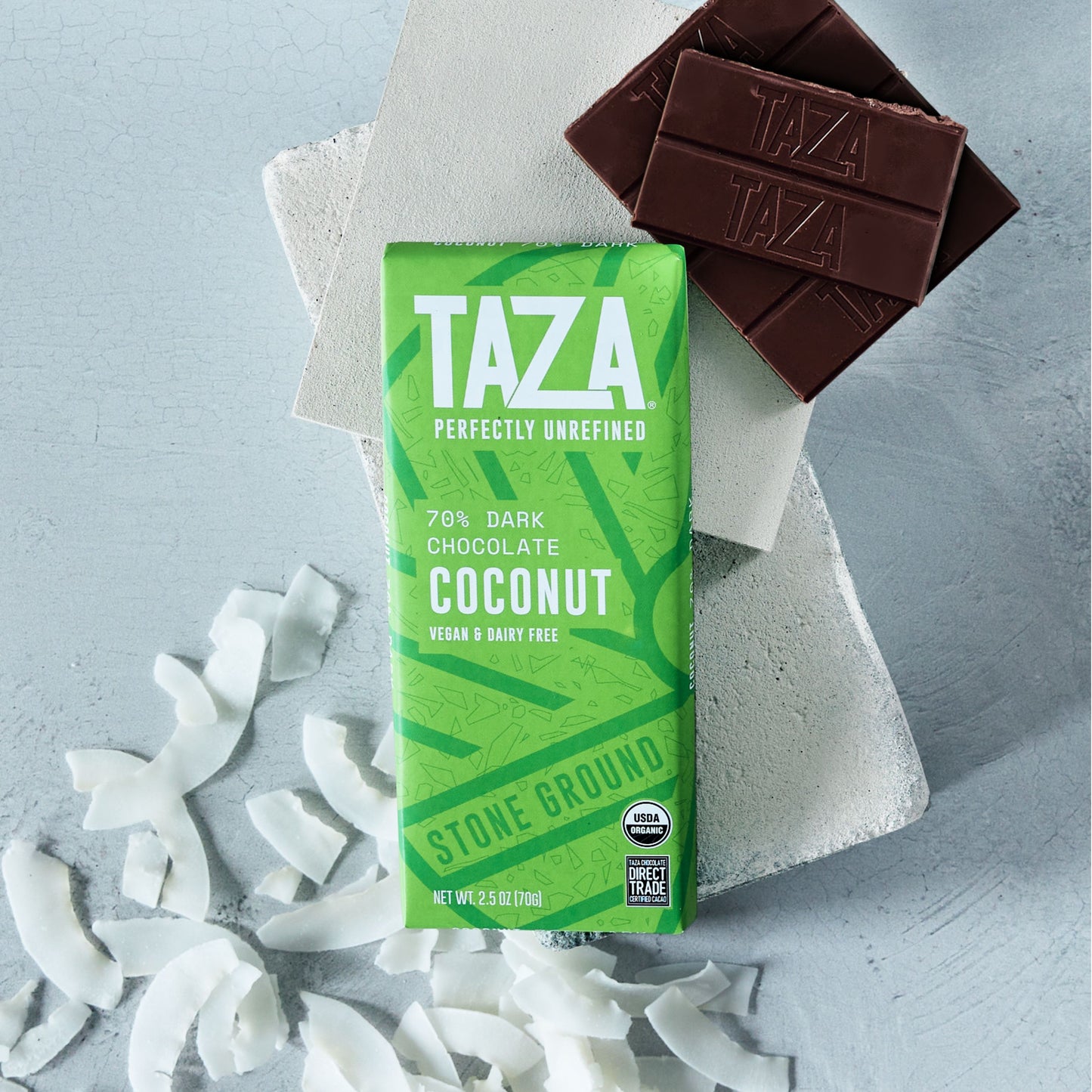Wrapped and unwrapped Coconut Chocolate Bar surrounded by coconut shavings.