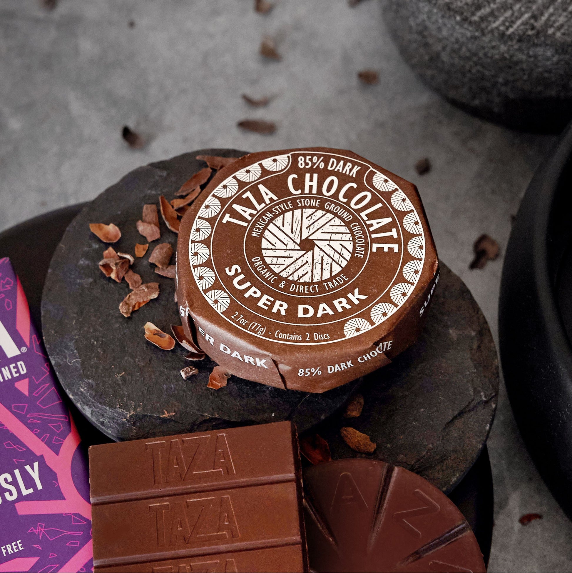 Super Dark Chocolate Disc surrounded by unwrapped chocolate.