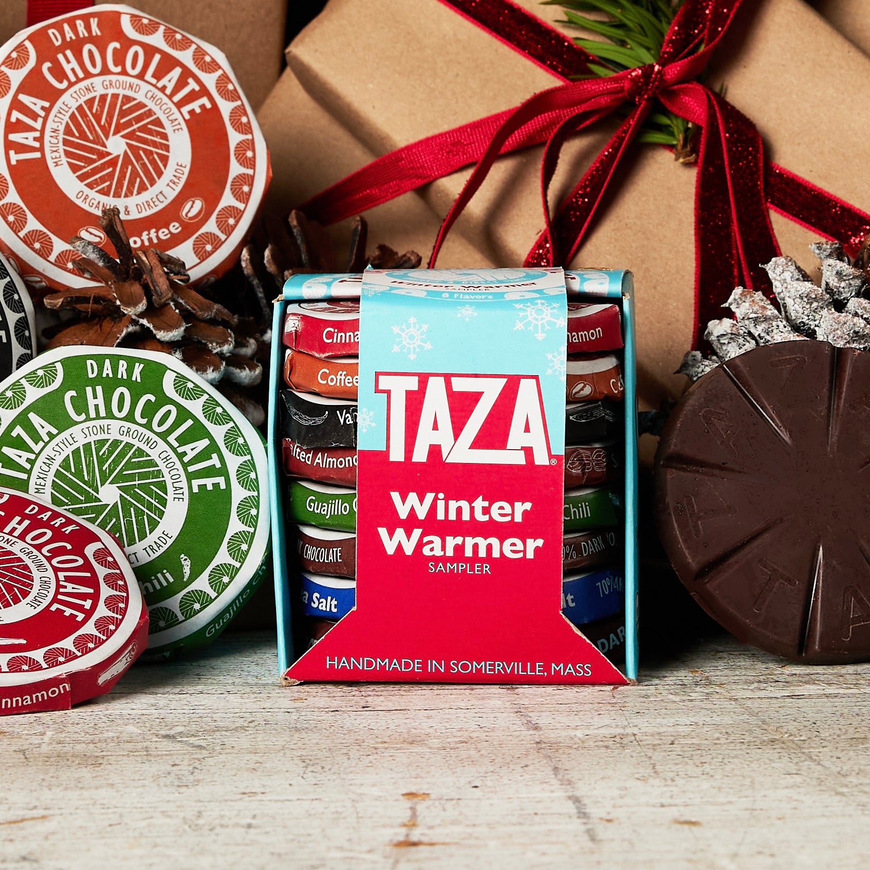 Taza chocolate Winter Warmer sampler box with holiday-themed packaging and a gift box in the background.
