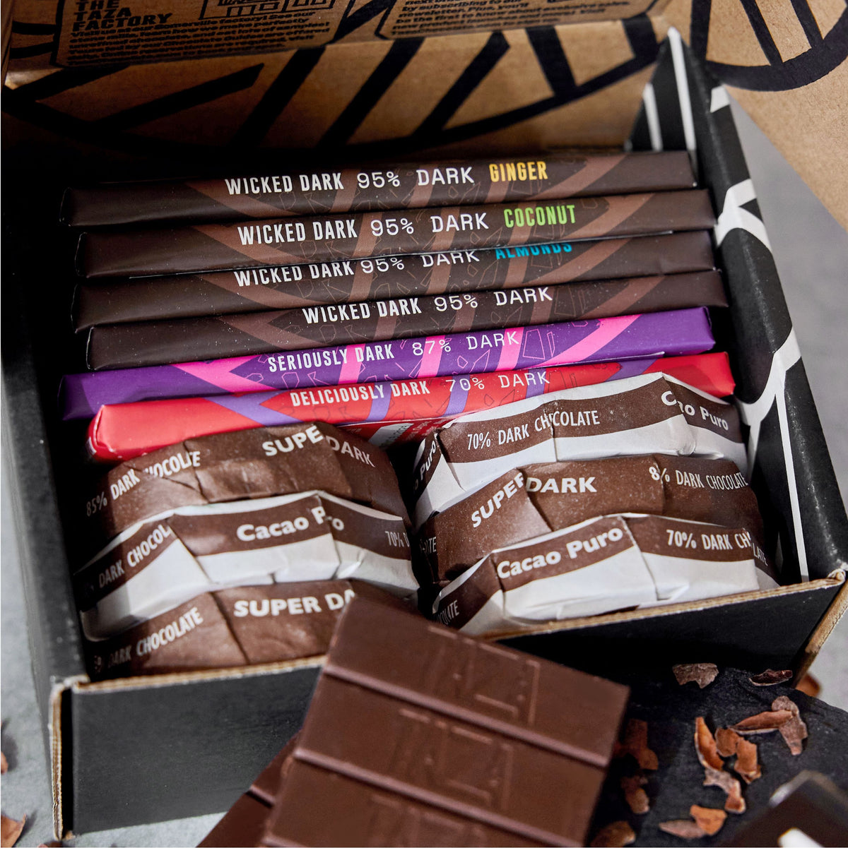 Open Taza dark chocolate gift box showing Wicked Dark bars, Seriously Dark bar, Deliciously Dark bar, Cacao Puro and Super Dark discs