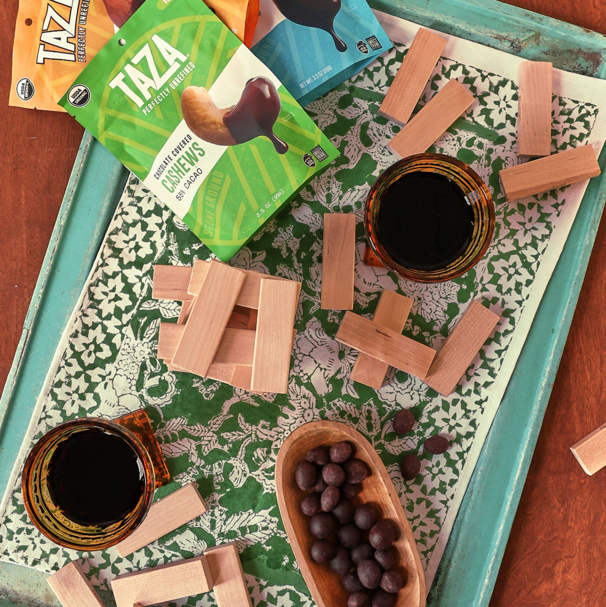 Bag of Chocolate Covered Cashews in a family game night setting with an open bowl of chocolate covered cashews.