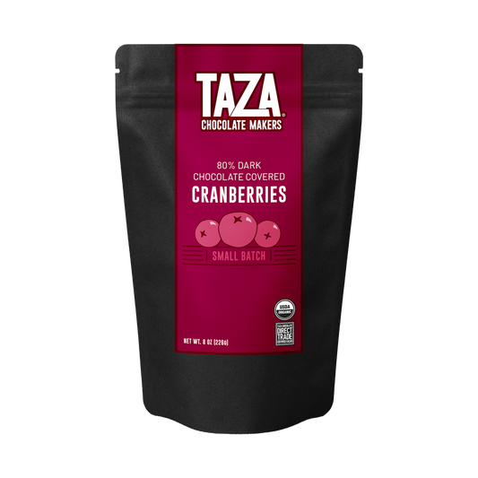 A black stand-up pouch of Taza Chocolate Makers 80% Dark Chocolate Covered Cranberries, featuring a prominent magenta label with white text and illustrations of cranberries.